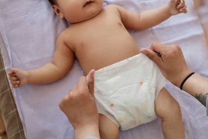 un bebé en un cambiador al que le están haciendo cambio pañal recién nacido