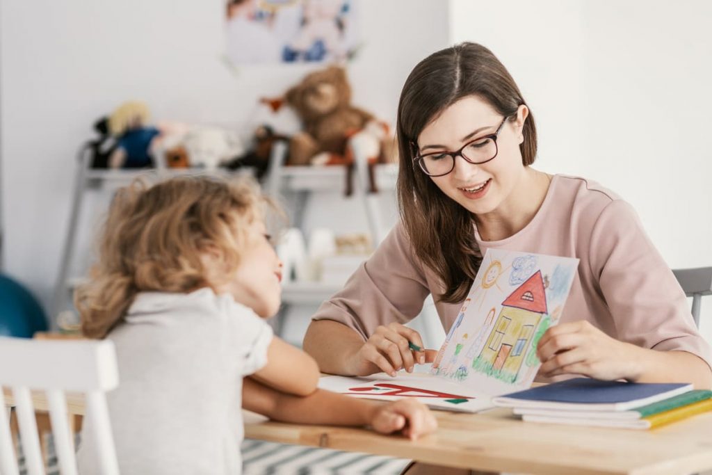 mujer profesional enseñando valores para niños a una niña con un dibujo