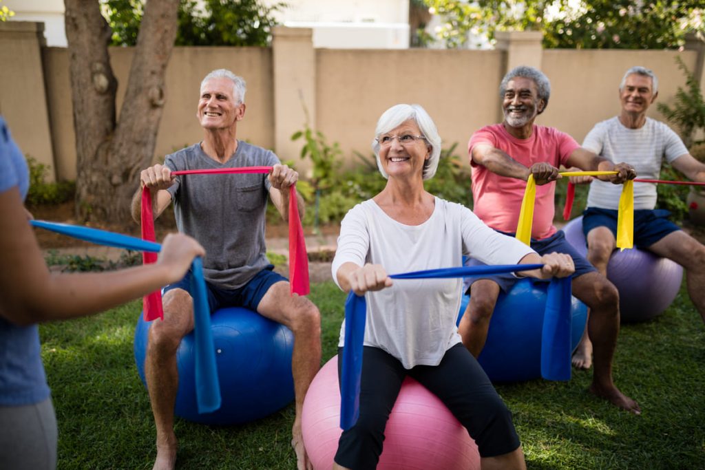 grupo de personas haciendo ejercicios para personas mayores con balón y gomas